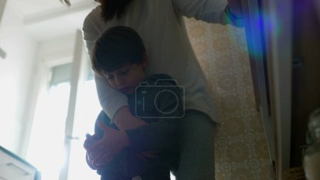 Téléchargez les photos : Mère et enfant suspendus à la cuisine, maman avec le bras autour du petit garçon dans la vraie scène de famille authentique. parent enfant relation - en image libre de droit