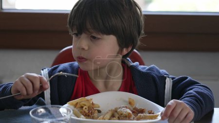 Photo for Child eating pasta, young boy enjoying rich-carb food, candid family lifestyle scene of 5 year old boy eating by himself - Royalty Free Image
