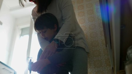 Photo for Mother and child hanging at kitchen, mom with arm around small boy in genuine authentic family scene. parent child relationship - Royalty Free Image