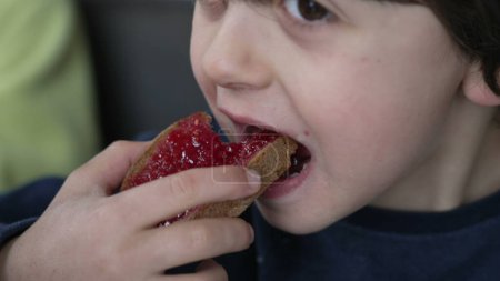 Photo for One Small Boy Eating Toast Bread with Jelly at Breakfast Table, Close-Up Face of Kid Taking a Bite of Food - Royalty Free Image