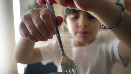 Foto de Primer plano de niño girando pasta de espaguetis con tenedor. Niño de 5 años que come alimentos ricos en carbohidratos durante la hora de la comida, niño que aprende a comer plato italiano - Imagen libre de derechos