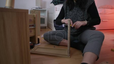 Téléchargez les photos : Femme assemblant des meubles à la maison, montage de maison bricolage mettant ensemble table de nuit - en image libre de droit