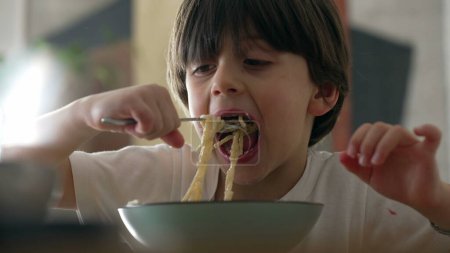 Joie au repas - Gros plan sur un petit garçon dégustant des spaghettis et savourant des pâtes riches en glucides