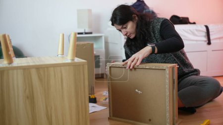 Téléchargez les photos : Femme assemblant des meubles, personne déménageant à un nouveau montage à la maison. Amélioration du bricolage - en image libre de droit