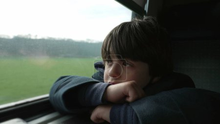 Photo for Thoughtful kid looking at scenery pass by from train. Contemplative 5 year old boy lost in thought staring at landscape from high-speed transportation, close-up face with arms crossed - Royalty Free Image