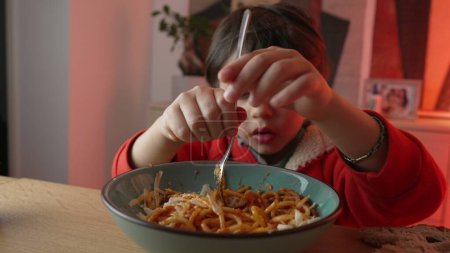 Photo for Little boy eating pasta, close-up face of 5 year old child twirling spinning spaghetti with fork by himself. kid dining - Royalty Free Image