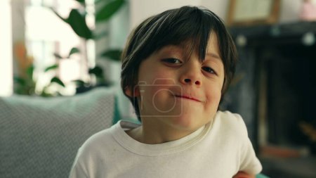 Téléchargez les photos : Jeune garçon de 5 ans portrait assis à la maison canapé, gros plan du visage joyeux garçon caucasien - en image libre de droit
