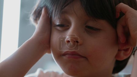 Foto de Pequeño niño pensativo con expresión ligeramente molesta contemplando solución al problema, primer plano de la cara de un niño de 5 años caucásico masculino en profunda reflexión mental - Imagen libre de derechos