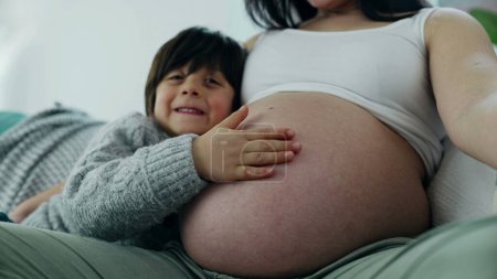 Photo for Happy small 5 year old boy gently rubs mother's pregnant belly during late stage of pregnancy. Happiness maternal concept between loving genuine family moment - Royalty Free Image