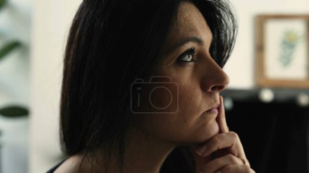 Photo for Contemplative 30s woman seeking solution to problem in deep thoughtful expression, close-up face indoors at residence home - Royalty Free Image