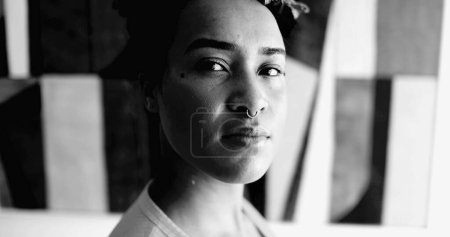 Mujer joven afroamericana retrato dramático en blanco y negro mirando a la cámara con expresión seria empoderada. 20s chica adulta sentirse seguro y fuerte en monocromo