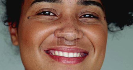One happy young black Brazilian woman of African descent smiling at camera in tight macro close-up facial detail smile with friendly demeanor