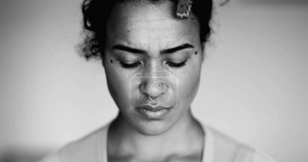 Photo for One anxious young black woman close-up face expressing preoccupation and mental despair in dramatic black and white. Desperate 20s person of African descent - Royalty Free Image