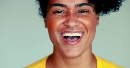 Téléchargez les photos : Une jeune femme afro-américaine heureuse en gros plan sourire et rire, expression authentique de la vie réelle d'une personne brésilienne réagissant à un commentaire drôle - en image libre de droit
