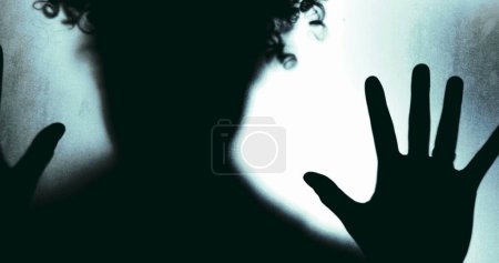 Photo for Silhouette of Individual Against Misty Glass in Despair, Struggling with Mental Illness. Hands pressing wanting to get out feeling alone and suffering of depression and isolation - Royalty Free Image