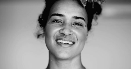 Photo for Happy black latina woman descent smiling at camera with friendly expression in black and white. Monochromatic portrait of brazilian young woman in her 20s - Royalty Free Image