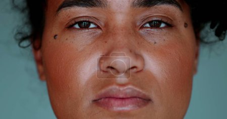 Photo for One young black woman staring at camera in macro close-up facial detail and solemn expression. Serious 20s female person of African descent - Royalty Free Image