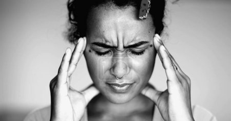 Foto de Abrumada joven afroamericana presionando las sienes de la cabeza sintiendo presión mental y ansiedad, la cara cercana de la persona siente estrés e indignación - Imagen libre de derechos