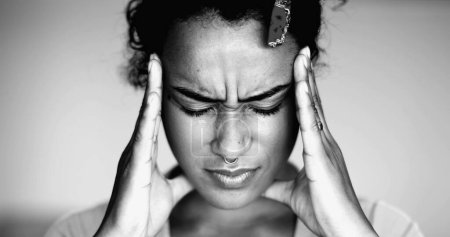 Foto de Abrumada joven afroamericana presionando las sienes de la cabeza sintiendo presión mental y ansiedad, la cara cercana de la persona siente estrés e indignación - Imagen libre de derechos