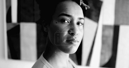 Eine junge afroamerikanische Frau mit dramatischem Schwarz-Weiß-Porträt, die mit ernstem Gesichtsausdruck in die Kamera blickt. 20er Jahre erwachsenes Mädchen fühlt sich in Monochrom selbstbewusst und stark
