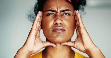 Photo for Young frustrated woman close-up face having a headache putting hands on side temples feeling mental pressure. Stressed out African American 20s person - Royalty Free Image