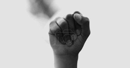 Foto de Puño de primer plano en el aire simbolizando el empoderamiento. Mujer afroamericana levanta la mano en el aire reclamando independencia y solidaridad en blanco y negro - Imagen libre de derechos