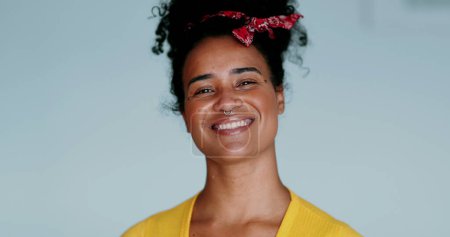 One happy young black Brazilian woman smiling with friendly demanor. Close-up face of a joyful 20s person of African descent on white background