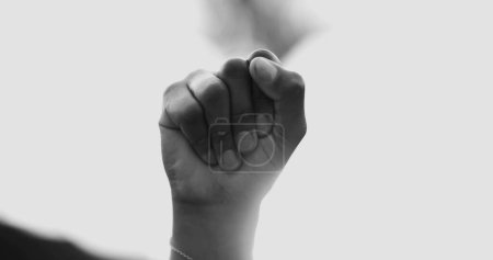 Photo for Close-up fist in the air symbolizing empowerement. African American woman raises hand in the air claiming independence and solidarity in black and white - Royalty Free Image