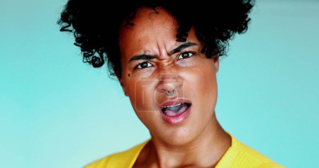 Foto de Una joven negra conmocionada reaccionando a noticias sorprendentes, mirando fijamente a la cámara con la boca abierta, emoción perpleja en los años 20 Dama, primer plano de la persona brasileña - Imagen libre de derechos