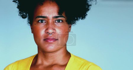 Una joven mujer negra reacciona negativamente a las noticias de notificación mirando directamente a la cámara con la boca abierta y el shock. Increíble emoción de la persona de 20 años