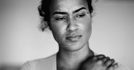 Una joven mujer negra preocupada retrato sintiendo ansiedad y preocupación durante los momentos difíciles en blanco y negro dramático. Millennial persona de ascendencia africana con pensativa emoción reflexiva