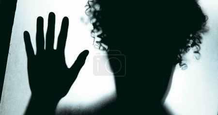 Photo for Desperate Person leaning on glass barrier, pressing hands against defocused window overwhelmed by depression and isolation. Mental health struggle depiction - Royalty Free Image