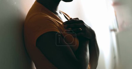 Téléchargez les photos : Une jeune femme noire spirituelle mettant la main sur la poitrine se sentant GRATITUDE. Sérieux Afro-Américain se sentant contemplation sincère appuyé sur le mur - en image libre de droit
