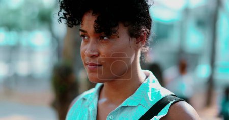 Photo for Portrait of a Pensive young black woman standing outdoor in peaceful meditative state, close-up face in tracking shot during sunny day and contemplative emotion - Royalty Free Image