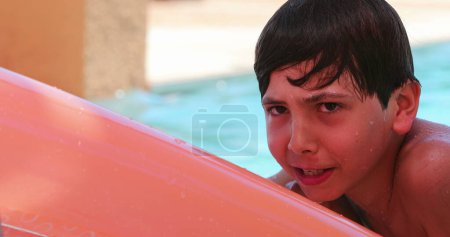 Foto de Niño cándido jugando en la piscina encima del colchón inflable - Imagen libre de derechos