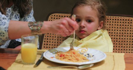 Photo for Child eating spaghetti for supper dinner mom feeding child food - Royalty Free Image