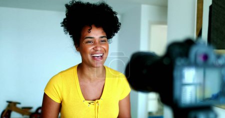 Photo for One young black woman speaking in front of camera giving testimony for online channel. 20s female vlogger creating video post engaged with new media - Royalty Free Image