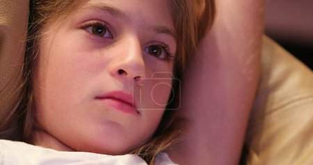 Foto de Primer plano de expresión de la cara del niño viendo la pantalla de cine aprendiendo sobre la historia - Imagen libre de derechos