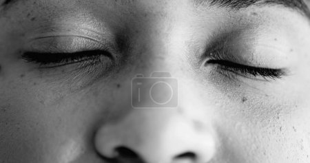 Foto de Mujer negra joven y serena en meditación, ojos cerrados y luego sonriendo a la cámara, macro primer plano de la transición facial de la contemplación a la alegría en blanco y negro, monocromo - Imagen libre de derechos