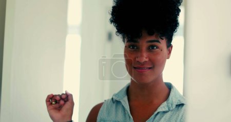 Photo for One joyful young black woman looking at herself in the mirror with confident gaze and sending a kiss to herself prepared to go out - Royalty Free Image