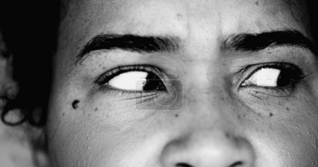 Foto de Una joven negra preocupada paranoica macro ojos cercanos mirando de lado con intensa preocupación y obsesión en dramático monocromo blanco y negro - Imagen libre de derechos