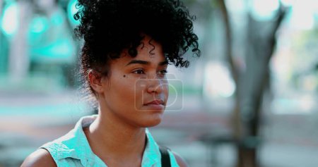 Téléchargez les photos : Portrait d'une jeune femme noire pensive debout en plein air dans un état de méditation paisible, le visage en gros plan dans le suivi des prises de vue pendant la journée ensoleillée et l'émotion contemplative - en image libre de droit