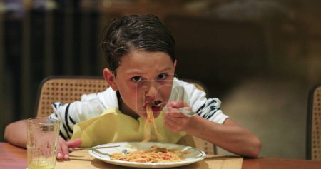Téléchargez les photos : Spaghettis pour le dîner jeune garçon manger le souper - en image libre de droit