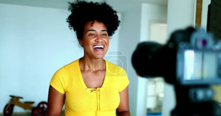 Una joven mujer negra hablando delante de la cámara dando testimonio para el canal en línea. 20s vlogger femenina creando post de vídeo comprometido con los nuevos medios