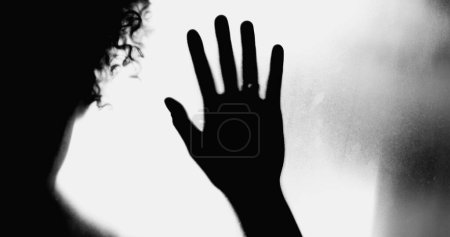 Photo for Silhouette of Person Leaning on Foggy Glass, Hands Pressed in Despair, Overcome by Depression, concept of mental illness feel desperate and alone during challenging times - Royalty Free Image