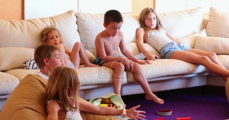 Téléchargez les photos : Enfants au salon canapé devant la salle de jeux TV enfants et amis ensemble - en image libre de droit