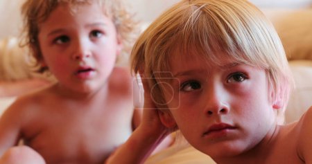 Foto de Niños pequeños viendo la pantalla de televisión hermanos rubios hipnotizados por el contenido de la película - Imagen libre de derechos