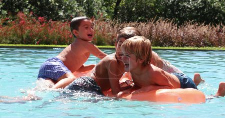 Foto de Los niños en la piscina en la parte superior del colchón inflable jugando riendo y sonriendo juntos - Imagen libre de derechos