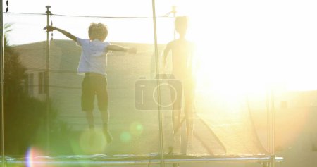 Photo for Children jumping inside trampoline outdoors - Royalty Free Image