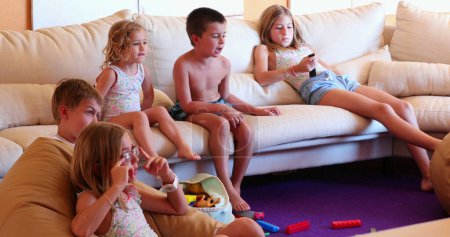 Téléchargez les photos : Enfants au salon canapé devant la salle de jeux TV enfants et amis ensemble - en image libre de droit